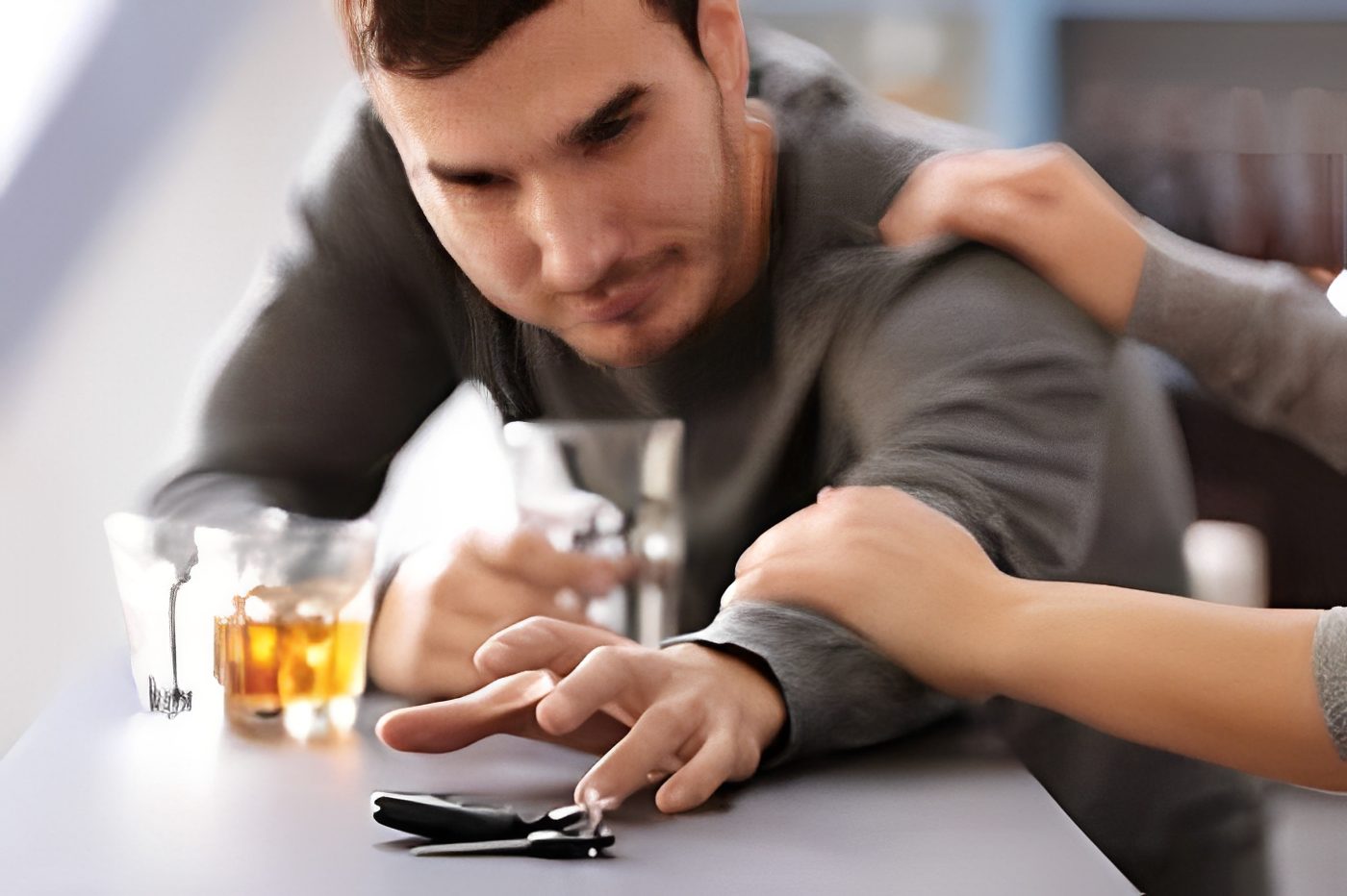 Man reaching for car keys, drink nearby