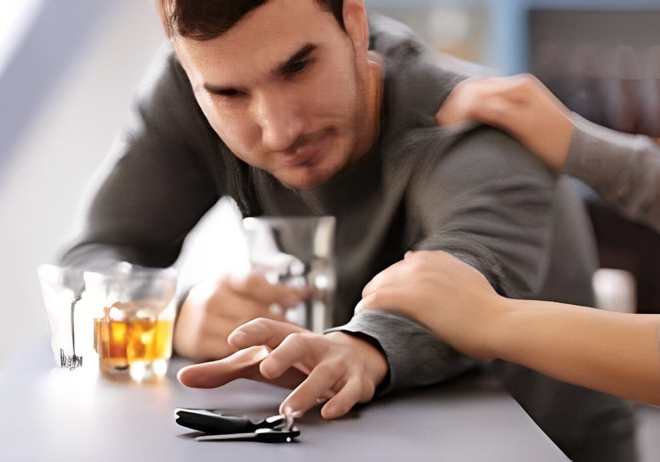 Man reaching for car keys, drink nearby